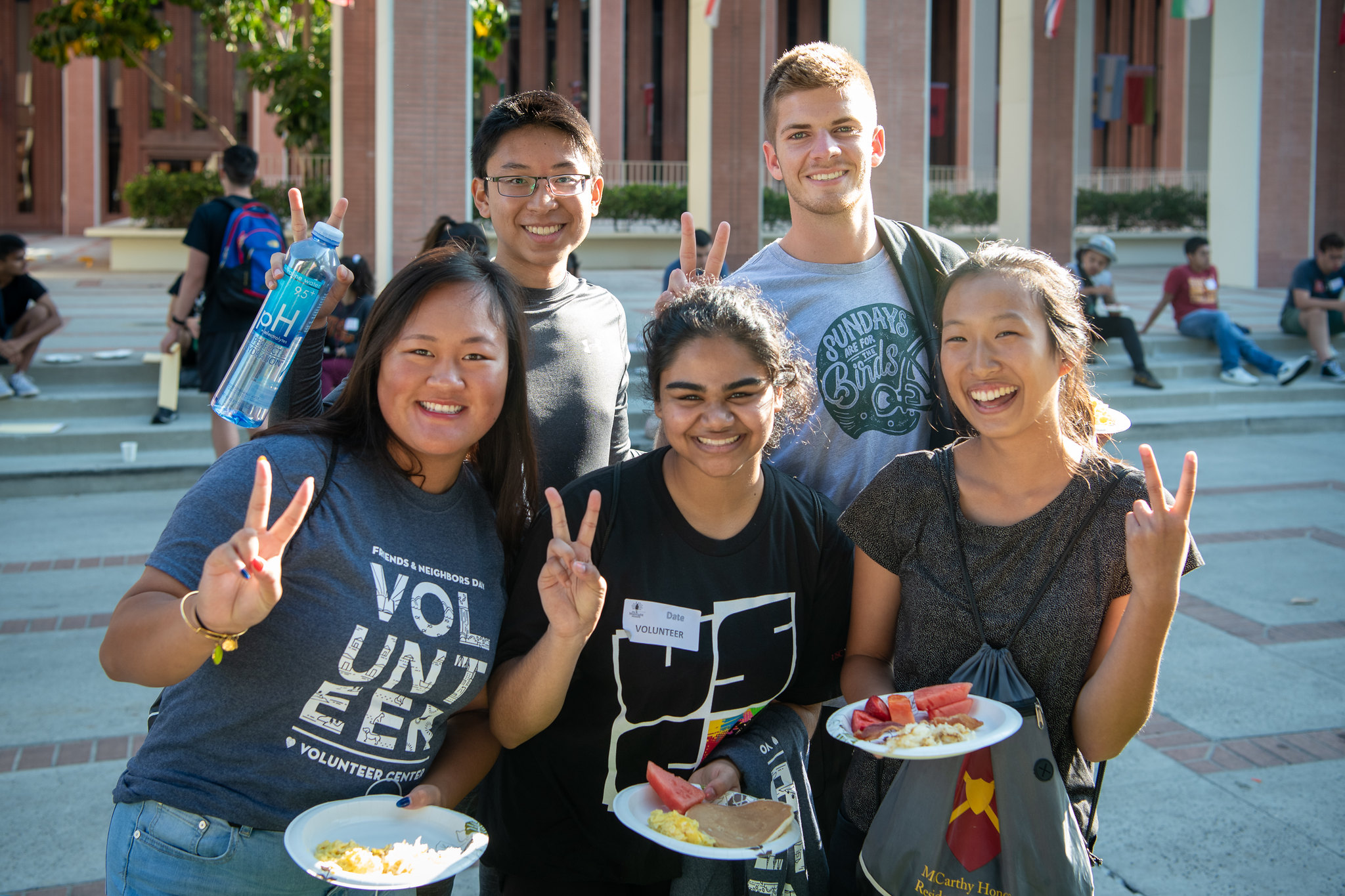 Five students throwing USC victory symbol