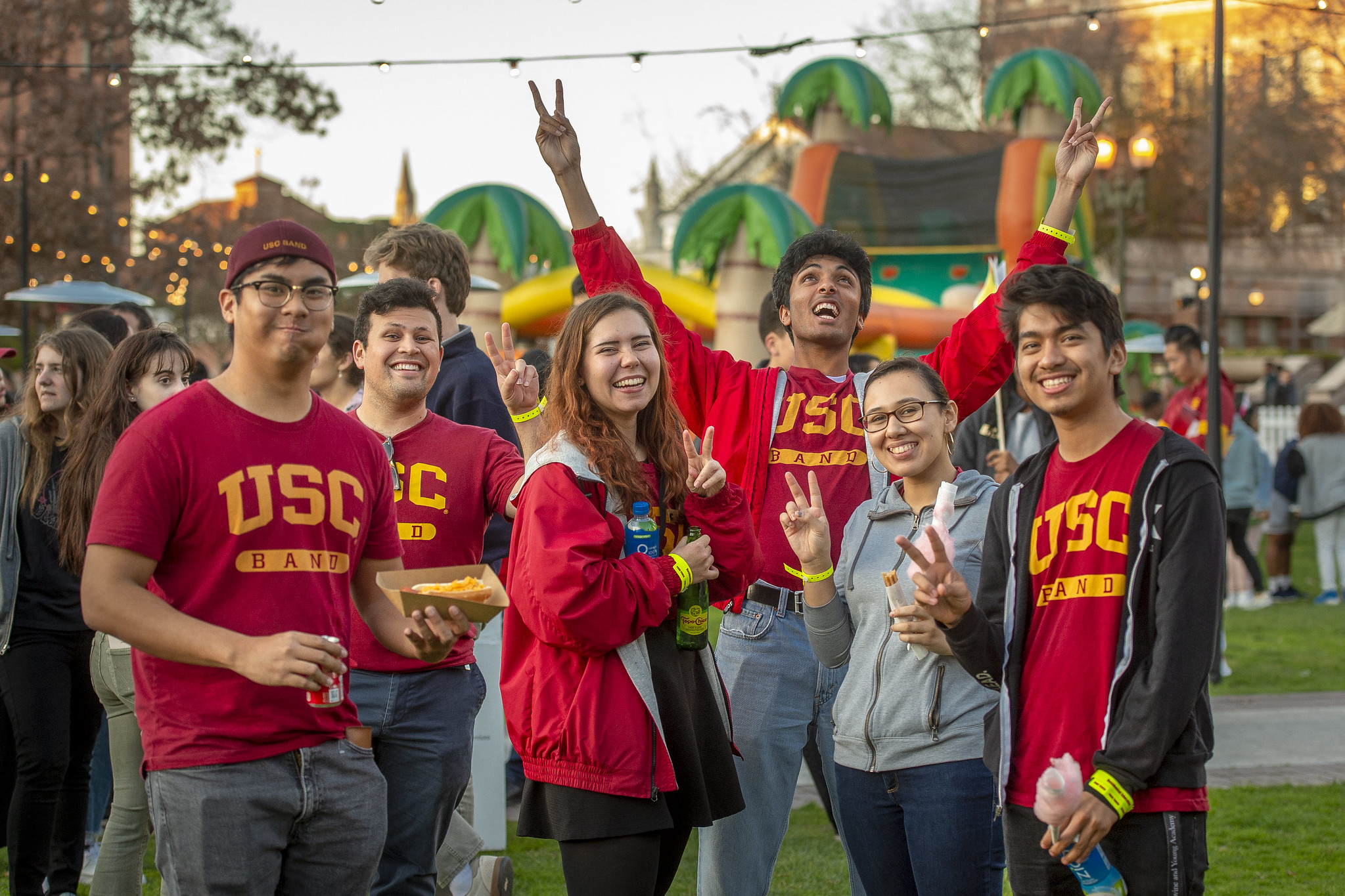Six students in USC shirts throwing USC victory symbol